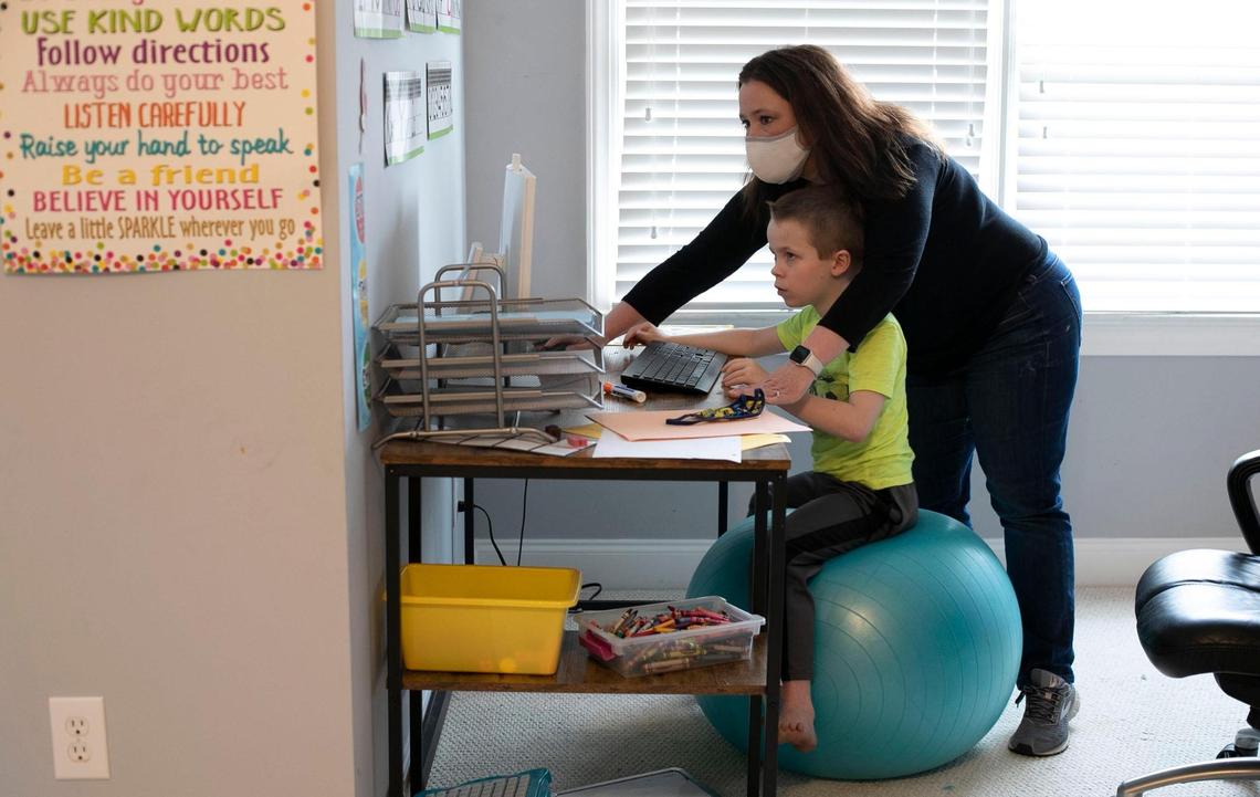 Lynda Manus works with her seven-year-old son Bryce Manus, a first-grader, to keep him focused on his virtual classes on Friday, March 26, 2021in Cary, N.C.