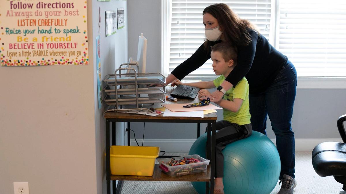 Lynda Manus works with her seven-year-old son Bryce Manus, a first-grader, to keep him focused on his virtual classes on Friday, March 26, 2021in Cary, N.C.