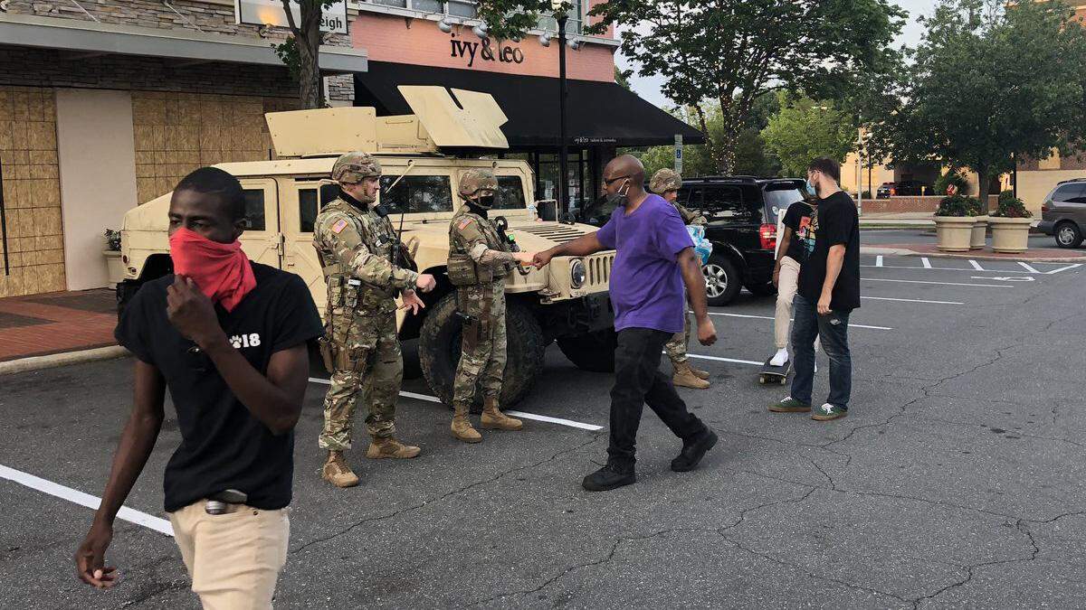A protester marching through Raleigh, N.C.’s Cameron Village fist-bumps a National Guardsman Saturday evening, June 6, 2020.