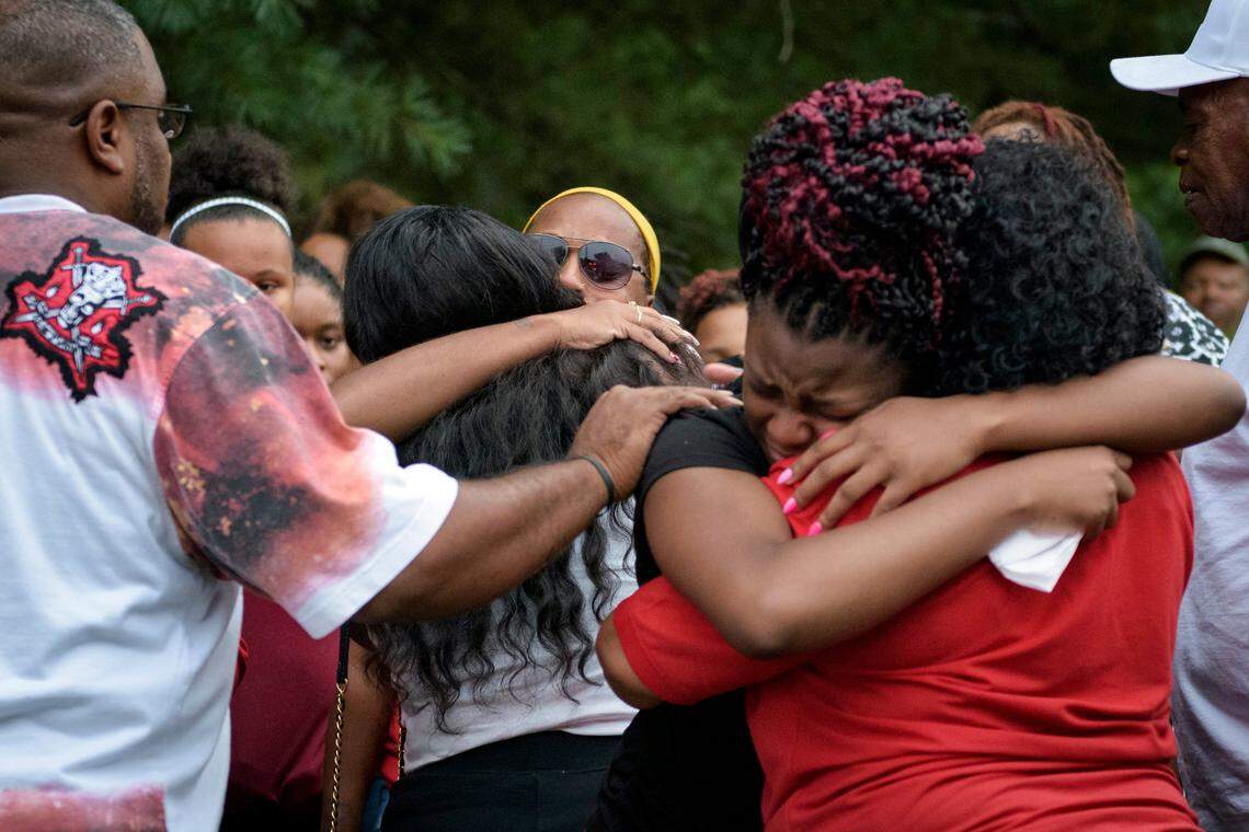 Z’yon Person’s mother, center, is embraced by friends and family members that attended the Sunday night vigil to remember and honor her 9-year-old son who was shot in a drive-by shooting.