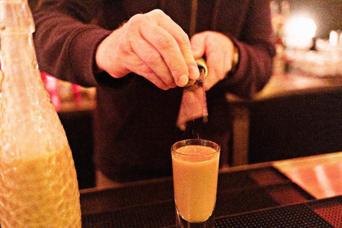 Justin Sykes, beverage director and manager at Jack Tar Restaurant & Lounge in Durham, grinds fresh nutmeg over two-year eggnog at the bar on Monday, Nov, 22, 2021.