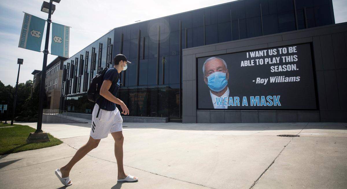 Walker Kessler, a UNC freshman and 2020 five-star basketball player, walks past an image of Roy Williams wearing a mask on the front of the Maurice J. Koury Natatorium in Chapel Hill, N.C. on Tuesday, Aug. 18, 2020.