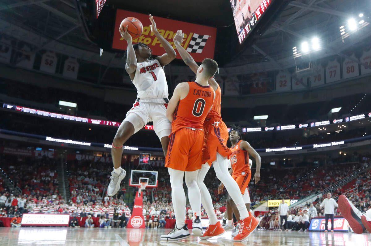 N.C. State’s Dereon Seabron (1) shoots as Virginia Tech’s Hunter Cattoor (0) and David N’Guessan (1) defend during Virginia Tech’s 62-59 victory over N.C. State at PNC Arena in Raleigh, N.C., Wednesday, Jan. 19, 2022.