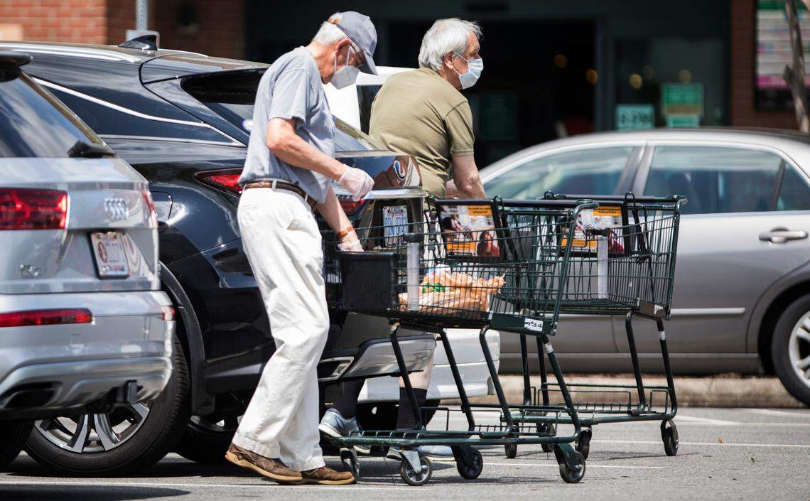 Customers of the Harris Teeter near University Mall in Chapel Hill unload their groceries in April while wearing masks and gloves. The company said on its website Thursday it will require customers to wear face coverings in all stores beginning July 22.