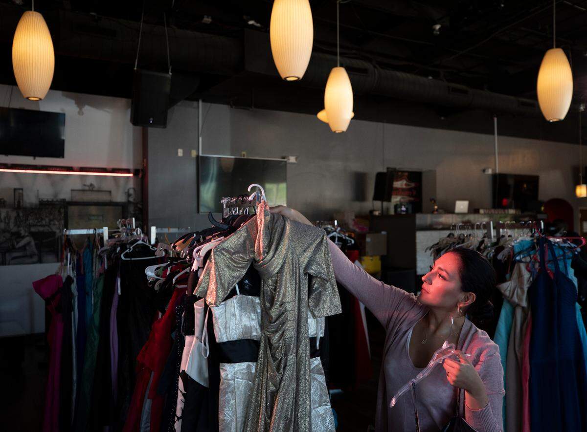 Natalie Garcia, a senior at Sanderson High School, looks through a rack of dresses during a prom dress drive held by the Hall Foundation on Wednesday, April 20, 2022, at Jonathan’s Sports Lounge & Grill in Raleigh, N.C.