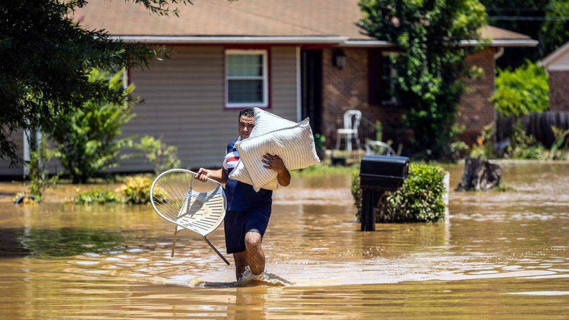 Naser Daher, of Durham’s Old Farm neighborhood, carries his belongings through floodwaters near the Eno River in Durham on Monday morning, July 7, 2025, after heavy rain from Tropical Storm Chantal caused flash flooding. Daher and his brother said they escaped the home with four children in the middle of the night as floodwater poured in.