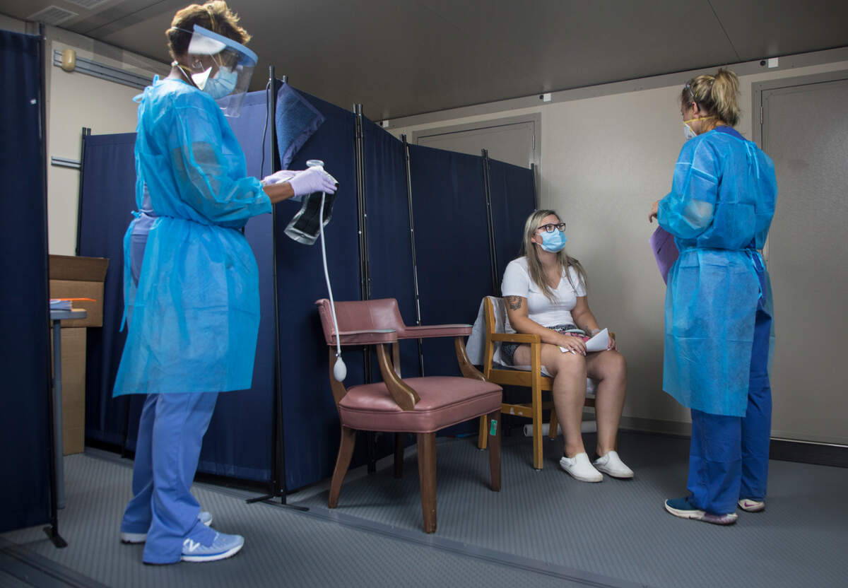 Emmily Mangum, middle, talks with health care workers Lauren Drapiza, right, and Talia Roofe, left, while under observation after receiving monoclonal antibody treatment for COVID-19 at a mobile clinic in the Johnston County Public Health Department parking lot in Smithfield, N.C., on Wednesday, Sept. 15, 2021.