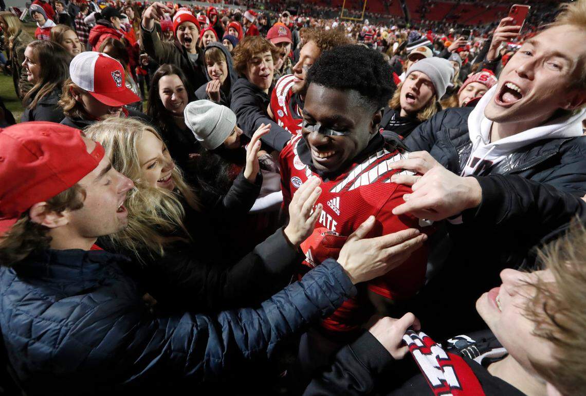 N.C. State wide receiver Emeka Emezie (86) is mobbed by fans who rushed the field after N.C. State’s 34-30 victory over UNC at Carter-Finley Stadium in Raleigh, N.C., Friday, November 26, 2021.
