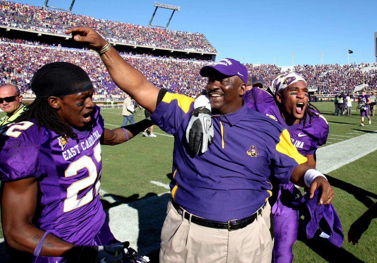 East Carolina’s Ruffin McNeill celebrates with Giavanni Ruffin (1), right, and Michael Bowman (22) after the Pirates’ 33-27 overtime victory over N.C. State in Greenville in 2010.
