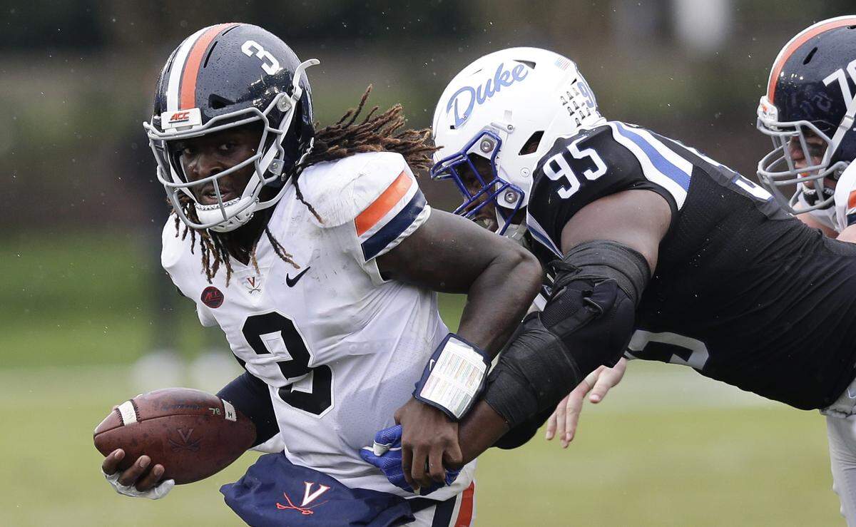 Virginia quarterback Bryce Perkins (3) runs while Duke defensive tackle Trevon McSwain (95) reaches for the tackle during the second half of an NCAA college football game in Durham, N.C., Saturday, Oct. 20, 2018. Virginia won 28-14.