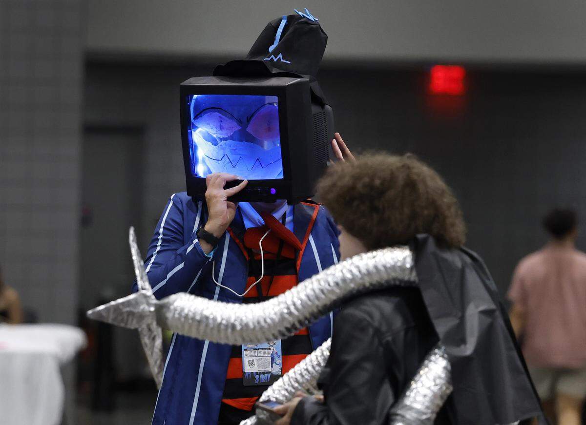 Jon Fisher of Asheville adjusts his head during GalaxyCon Raleigh at the Raleigh Convention Center Friday, July 25, 2025. Fisher is cosplaying Vox from Hazbin Hotel.