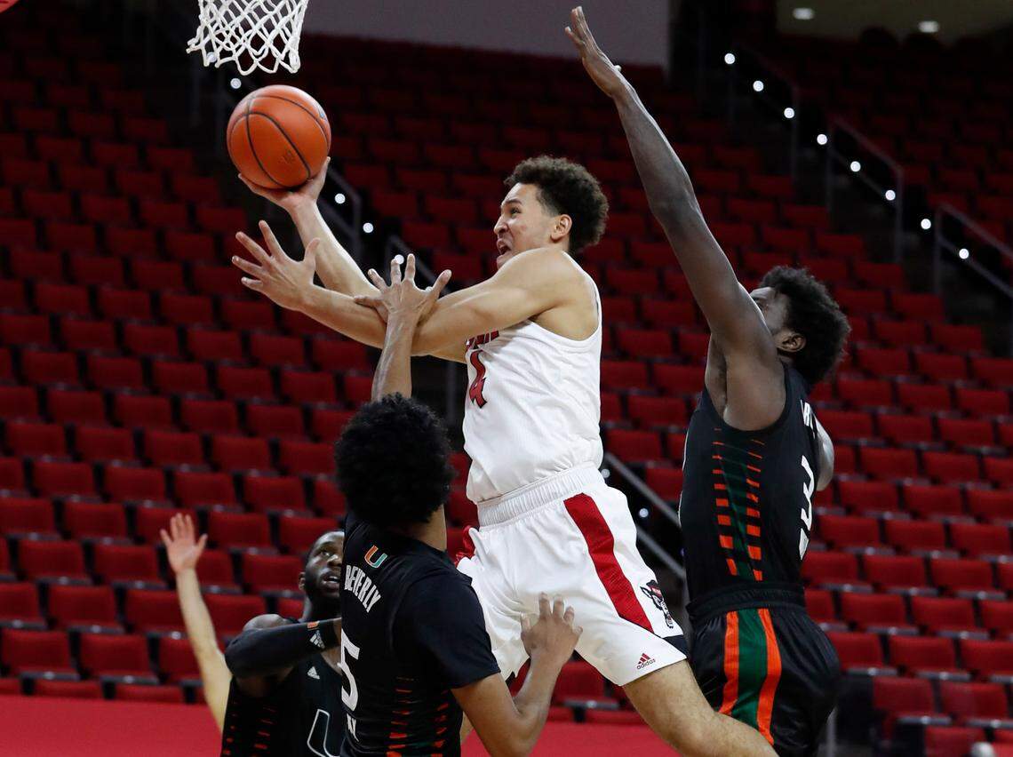 N.C. State’s Jericole Hellems (4) drives to the basket past Miami’s Harlond Beverly (5) and Nysier Brooks (3), right, during the first half of N.C. State’s game against Miami at PNC Arena in Raleigh, N.C., Saturday, January 9, 2021.