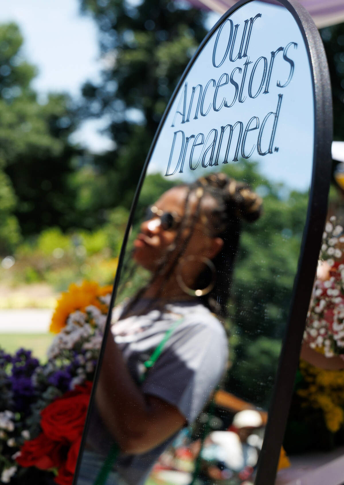 Sa’Metria Jones is reflected in a mirror while shopping at a floral vendor during a Juneteenth celebration in Moore Square on Thursday, June 19, 2025, in Raleigh, N.C.