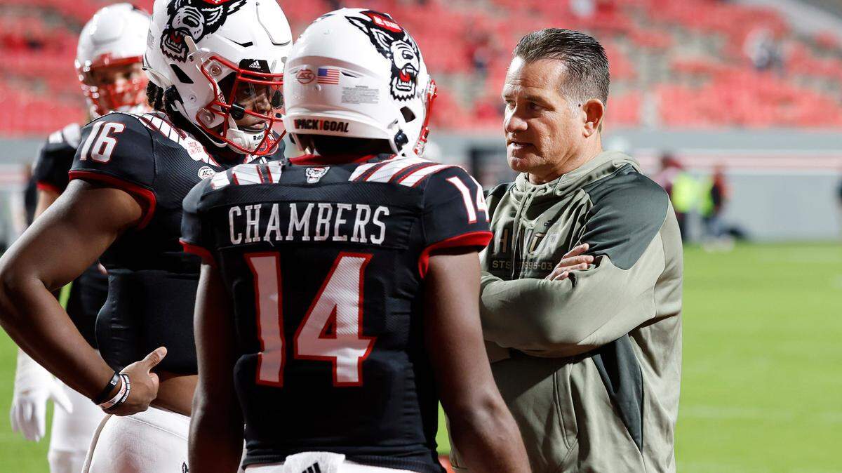N.C. State offensive coordinator Tim Beck talks with quarterbacks MJ Morris (16) and Jack Chambers (14) as they warm up before N.C. State’s game against Virginia Tech at Carter-Finley Stadium in Raleigh, N.C., Thursday, Oct. 27, 2022.