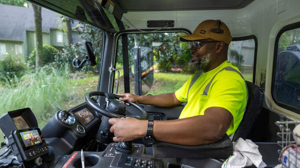 Raleigh Solid Waste Services employee Alonzo Adams collects household garbage using an automated side loader from the cockpit of his truck to empty curbside containers on Wednesday, July 17, 2024 in Raleigh, N.C.