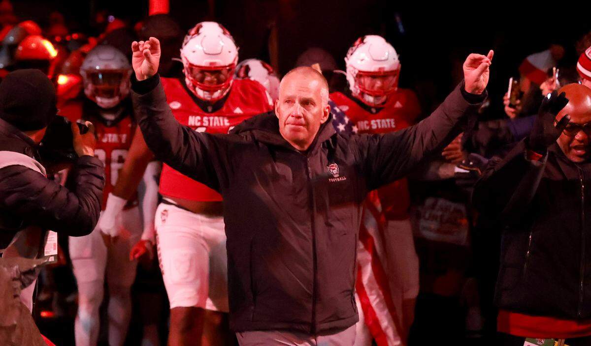 N.C. State coach Dave Doeren motions to the fans as the team gets ready to run out onto the field before the Wolfpack’s game against UNC at Carter-Finley Stadium in Raleigh, N.C., Saturday, Nov. 29, 2025.