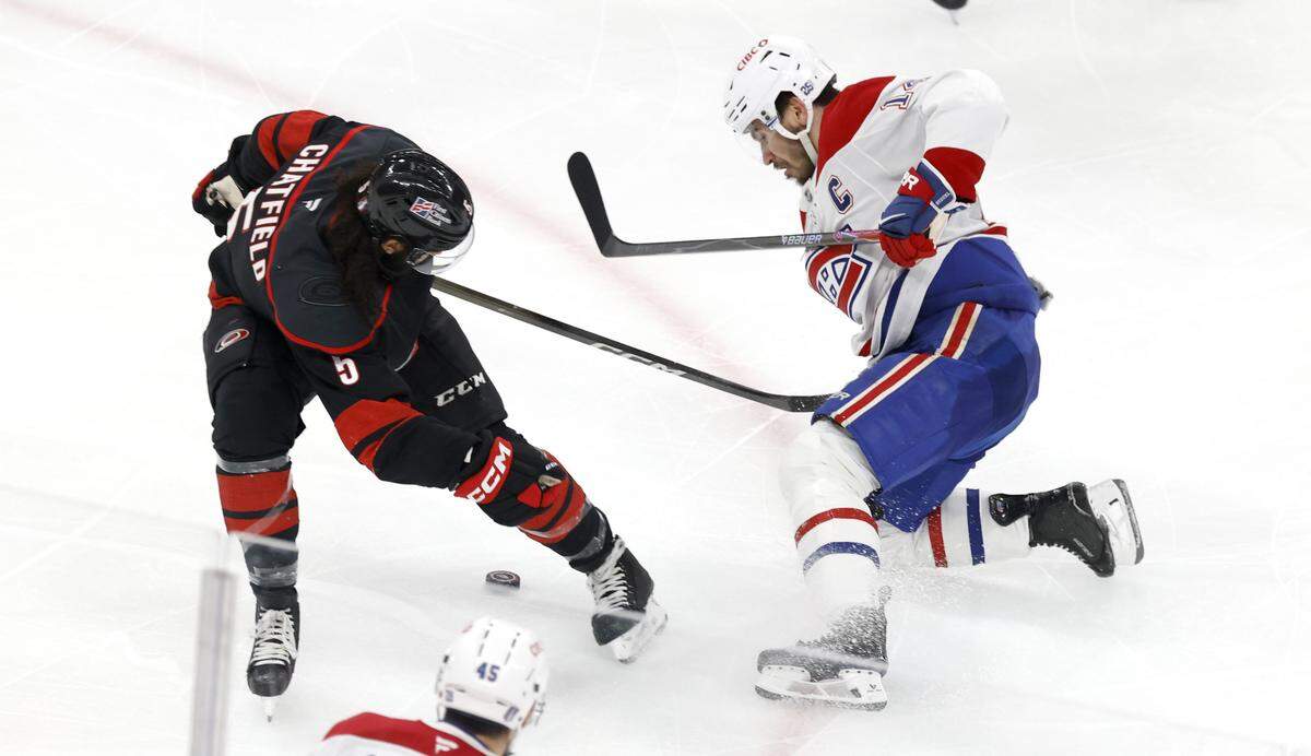 Carolina's Jalen Chatfield (5) tries to keep the puck from Montréal's Nick Suzuki (14) in the second period of the Hurricanes’ game against the Canadiens in game two of the Eastern Conference Finals at the Lenovo Center in Raleigh, N.C., Saturday, May 23, 2026.