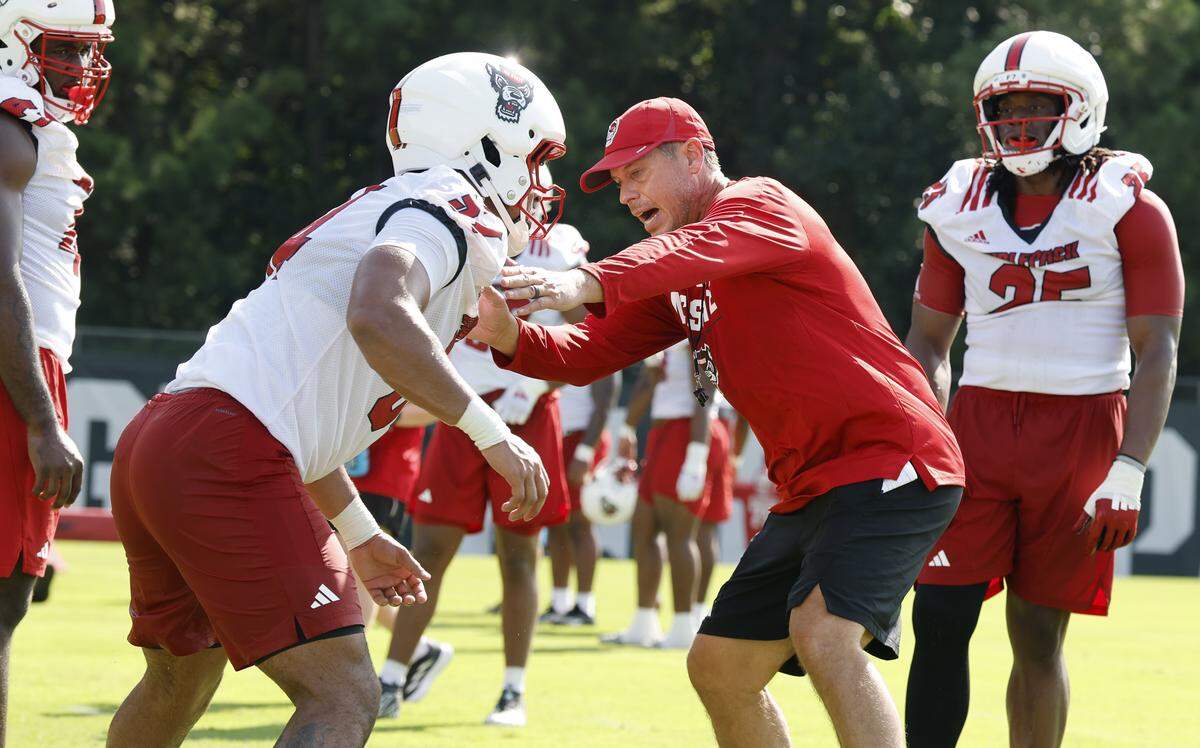 N.C. State defensive coordinator DJ Eliot demonstrates a drill while working with Sabastian Harsh (54) during the Wolfpack’s first fall practice Wednesday, July 30, 2025.