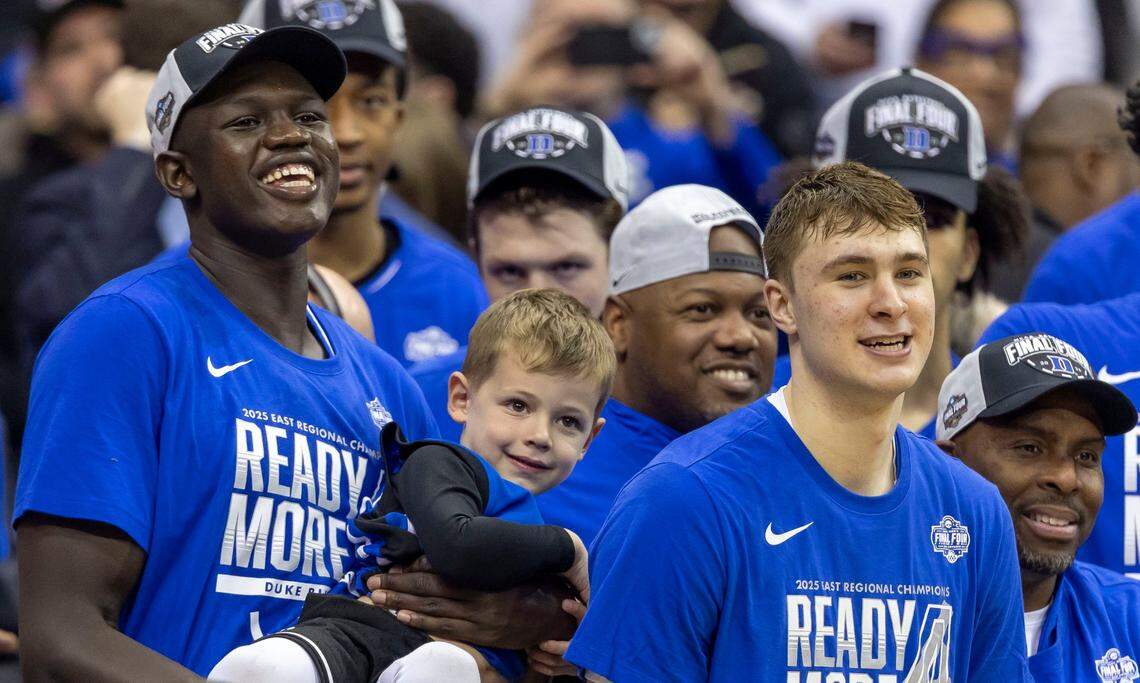 Duke center Khaman Maluach (9) cradles Jett Scheyer, Jon Scheyer’s son, as he and teammate Cooper Flagg (2) watch assistant coach Chris Carrawell cut down the net following the Blue Devils 85-65 victory over Alabama on Saturday, March 29, 2025 during the NCAA East Regional final at Prudential Center in Newark, N.J.