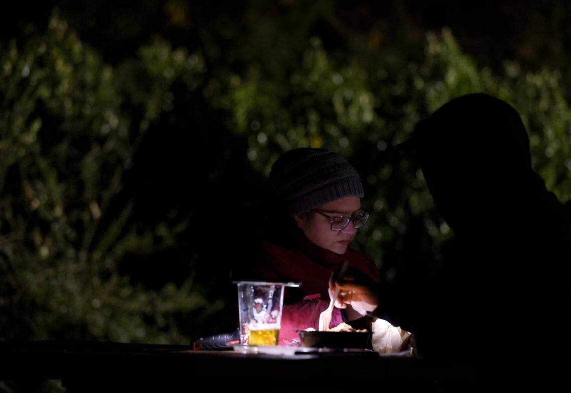 Molly Papp and James Childers eat by the light of a cell phone and flashlight at Red’s Corner during the Moore County power outage on Monday, Dec. 5, 2022, in Southern Pines, N.C.