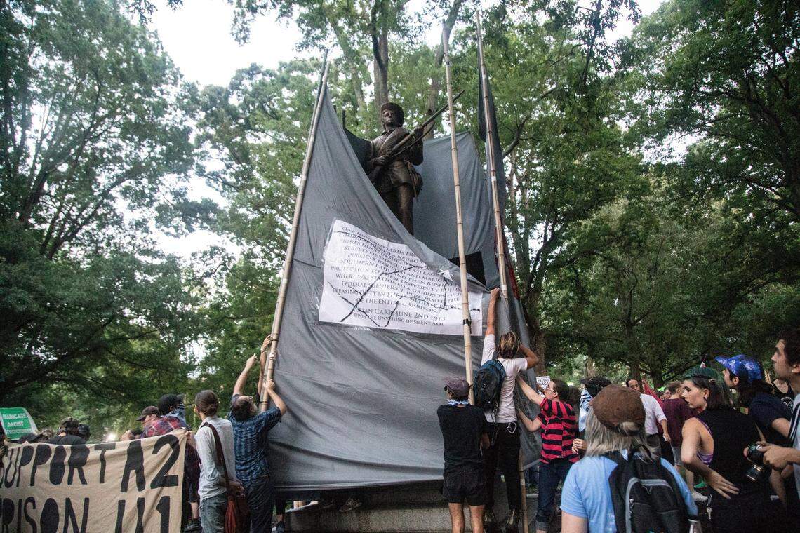 Demonstrators cover the a Confederate statue known as Silent Sam with banners Monday, August 20, 2018 at UNC-Chapel Hill. Demonstrators surrounded and obscured the statue with large banners before toppling it.
