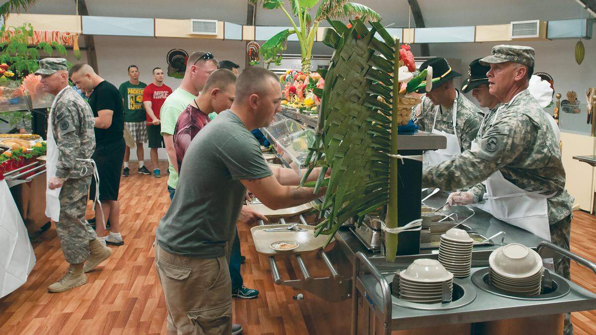 Army Master Sgt. Gregg Ramsdell, right, senior enlisted adviser to Joint Task Force Guantanamo’s commend element, hands over a plate filled with tradition Thanksgiving fare as members of the JTF leadership serve the holiday mean to Troopers at the Seaside Galley, Nov. 28, 2013. Senior leaders from throughout JTF GTMO, Joint Detention Group and the Joint Medical Group served the Thanksgiving meal to Troopers.