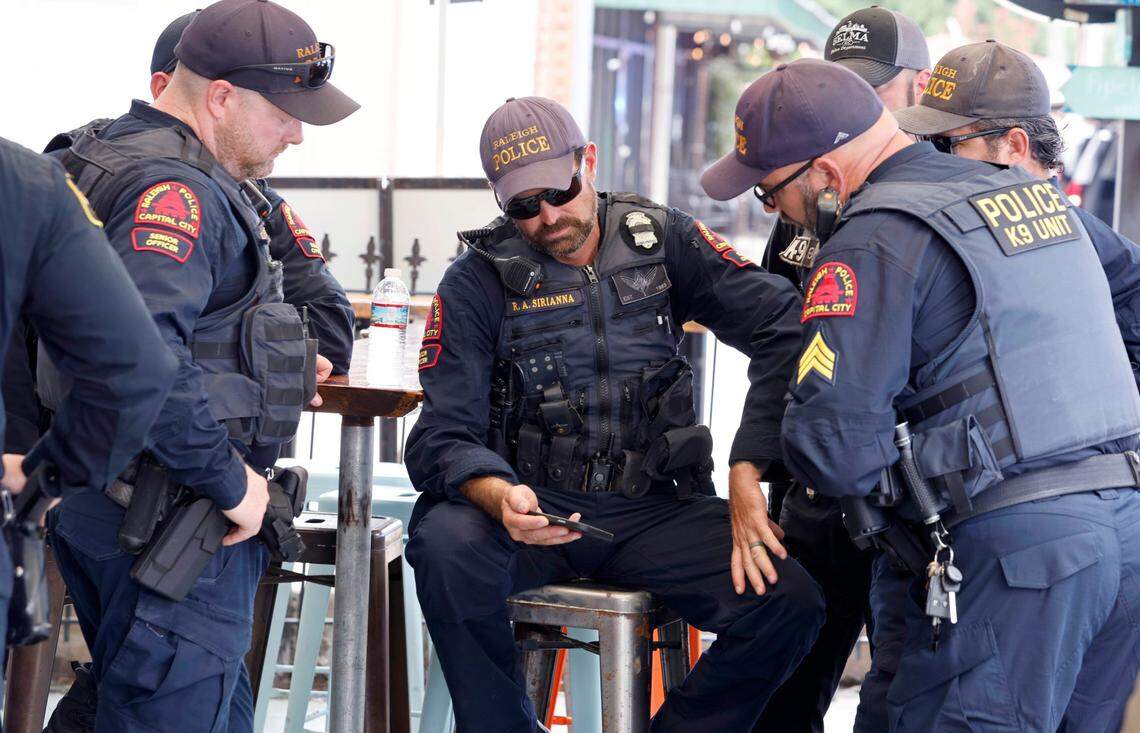 Raleigh police officers watch the funeral services for slain Wake County Sheriffs Deputy Ned Byrd in the Five Points neighborhood of Raleigh, N.C., Friday, August 19, 2022. The officers were there to honor Deputy Byrd as the procession drove down Glenwood Avenue.