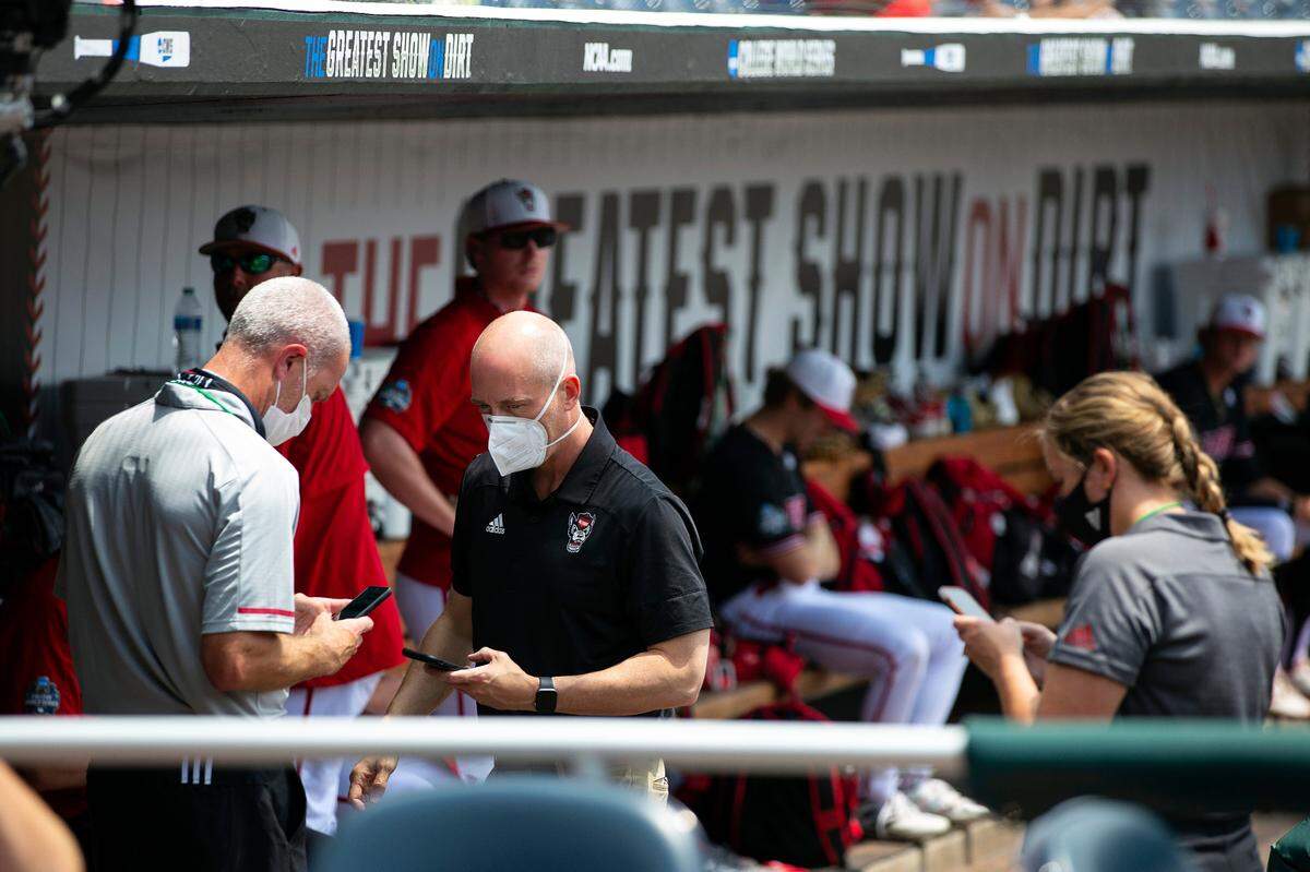 North Carolina State personnel chat in the dugout during a delay due to COVID-19 safety protocols before their baseball game against Vanderbilt in the College World Series Friday, June 25, 2021, at TD Ameritrade Park in Omaha, Neb. (AP Photo/Rebecca S. Gratz)