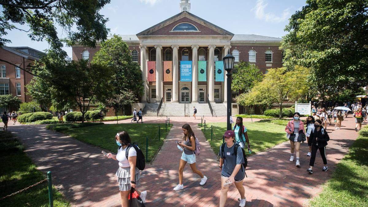 Students at UNC-Chapel Hill walk past Carroll Hall, which houses the Hussman School of Journalism and Media, in Chapel Hill, N.C. on Friday, Aug. 27, 2021.