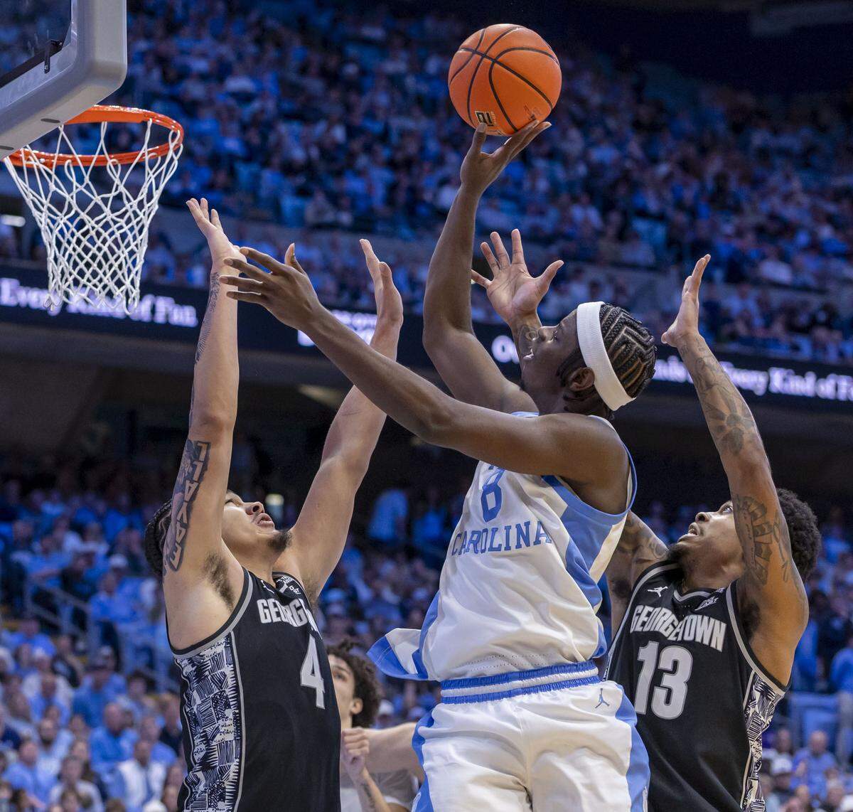 North Carolina forward Caleb Wilson (8) puts up a shot against Georgetown forward Jaydon Young (4) and guard Langston Love (13) in the second half on Sunday, December 7, 2025 at the Smith Center in Chapel Hill, N.C.  Wilson lead the Tar Heels with 20 points in their 81-61 victory.