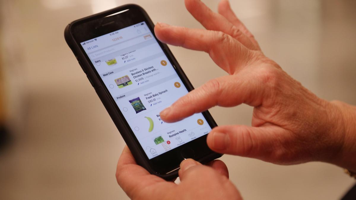 A shopper using her phone inside of a Wegmans grocery store.