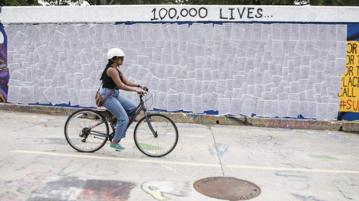 On Tuesday, May 26 a cyclist rides past 100 copies of a list of 1,000 victims of COVID-19 that was published on the front page of The New York Times newspaper on Sunday, May 24. The copies were plastered to the wall at the end of the free expression tunnel on Duke University’s East Campus on Monday night by twin brothers Oliver and Leo Egger, 18, of Durham, N.C.