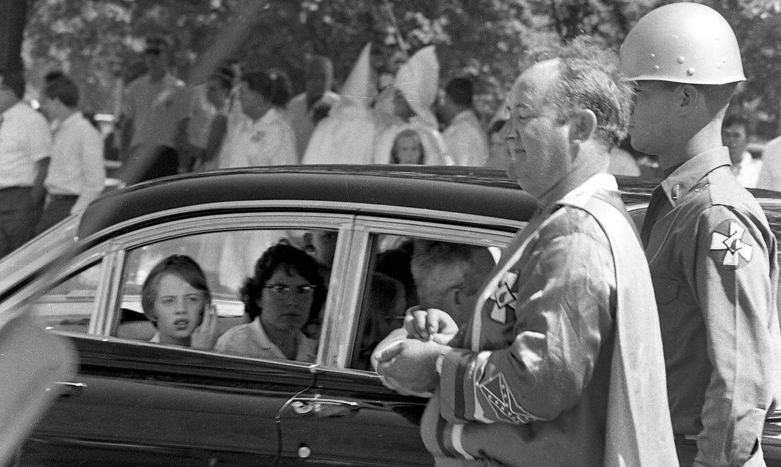 A young girl looks out of a car window at members of the KKK marching in downtown Raleigh near Nash Square, July 31, 1966. Dr. Martin Luther King Jr. spoke later that day at NC State’s Reynolds Coliseum.