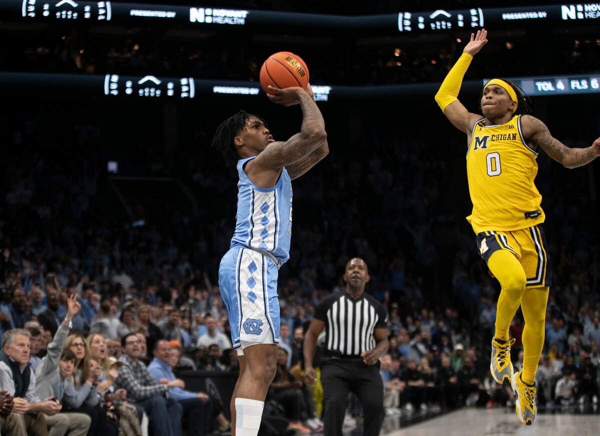 North Carolina’s Caleb Love (2) launches a three point shot as Michigan’s Dug McDaniel (0) tries to defend in the second half on Wednesday, December 21, 2022 at the Spectrum Center in Charlotte, N.C.