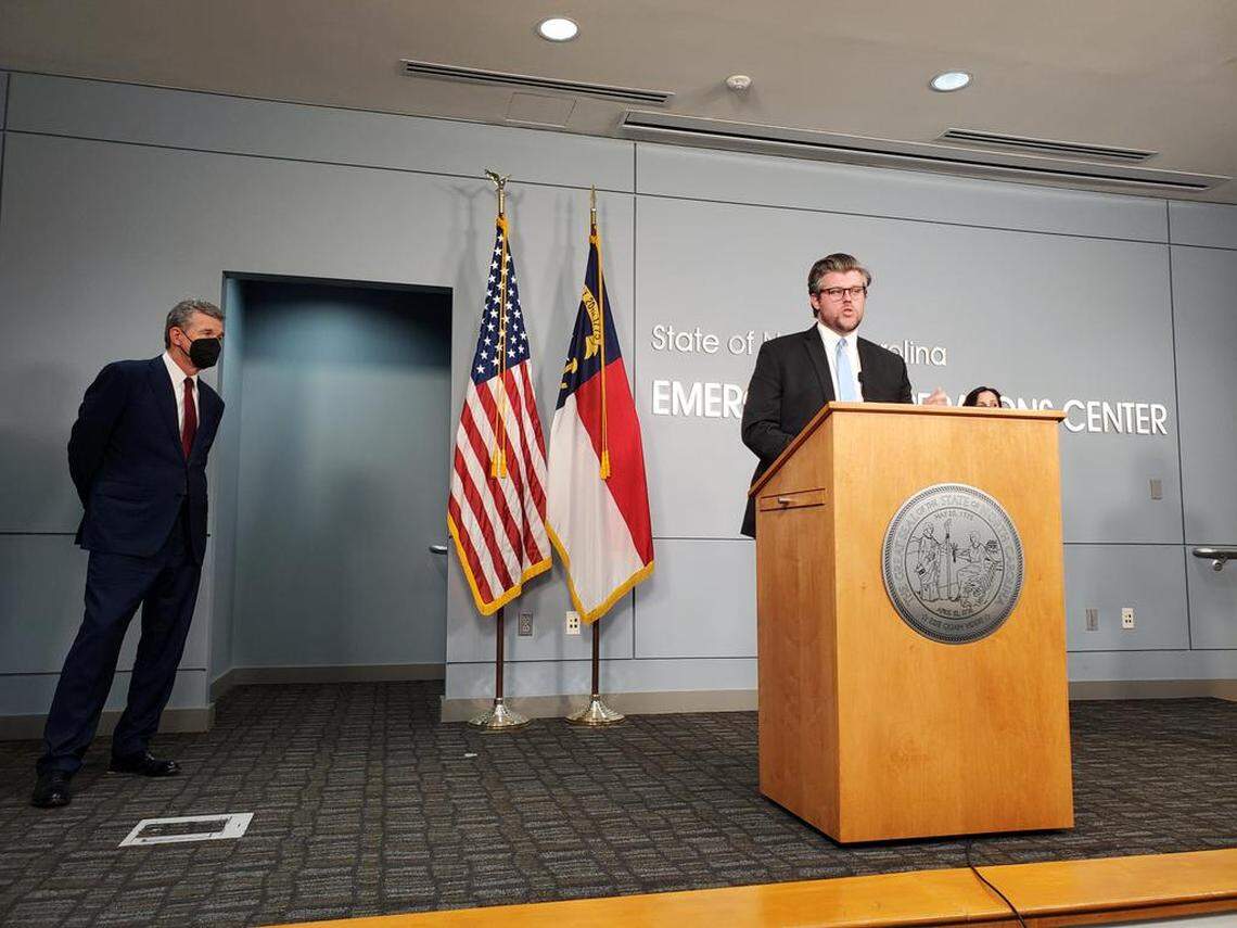 N.C. DHHS Secretary Kody Kinsley, at lectern, talks to reporters during a press briefing on COVID-19 on Thursday, Feb. 17, 2022 along with Gov. Roy Cooper, left.