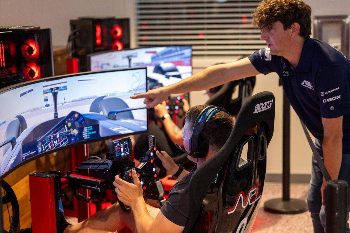 Adam Perrell helps guide Maverick Bostic and Ashlee Salazar during a racing simulation at Apex Racing Lab on Saturday, July, 13, 2024. The business features 16 racing simulators, a conference room, a craft cocktail bar and a gear shop, selling racing equipment.