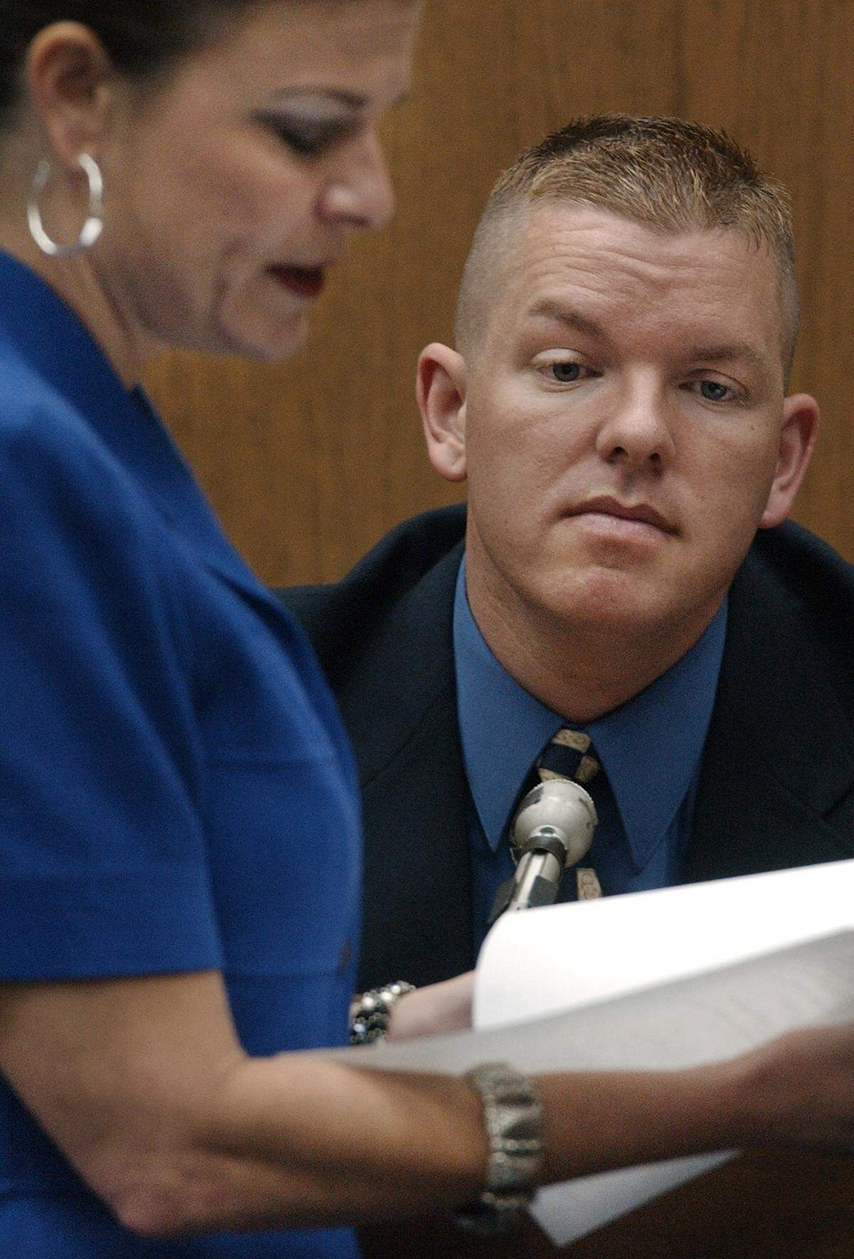 Self-described male escort Brent Wolgamott,28, of Raleigh,NC looks over a phone bill with assistant DA Freda Black as he testifies in the Michael Peterson murder trial.