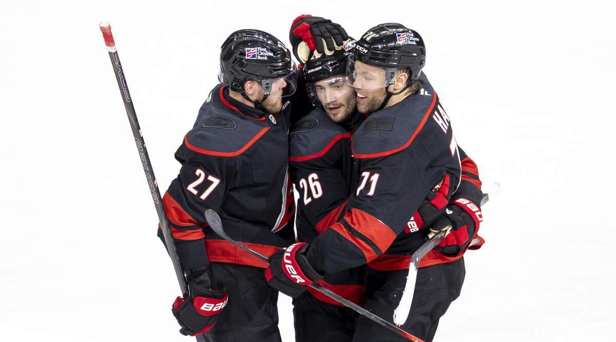 Carolina Hurricanes left wing Taylor Hall (71) embraces teammates Sean Walker (26) and Nikolaj Ehlers (27) after scoring the game winning goal  to secure a 3-2 overtime victory over Philadelphia, in Game 2 on Monday, May 4, 2026, during the second round of the Stanley Cup Playoffs at Lenovo Center in Raleigh, N.C.