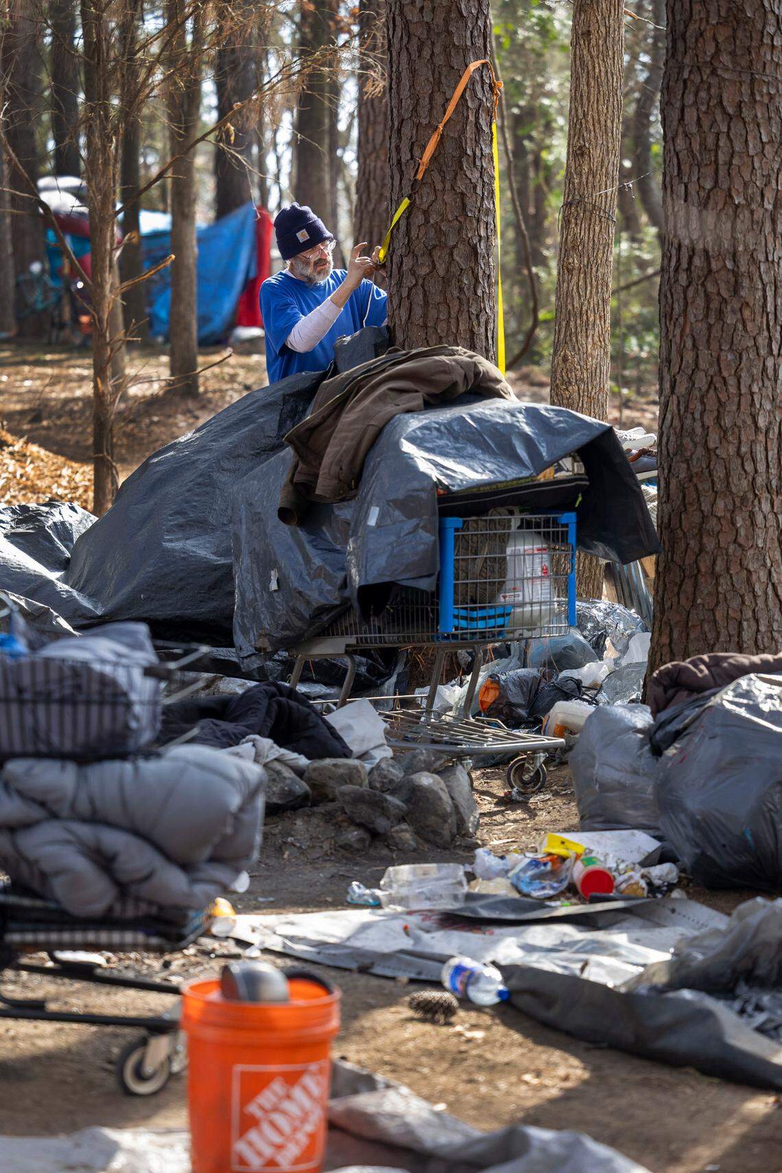 Kenneth Edwards packs up his tent, tarps and personal belongings in an encampment along Goode Street, adjacent to the State Farmers Market, on Friday, January 31, 2025 in Raleigh, N.C. Edwards said he had been living here since Halloween 2024. The property was recently posted, asking that the land be vacated by January 31, 2025.