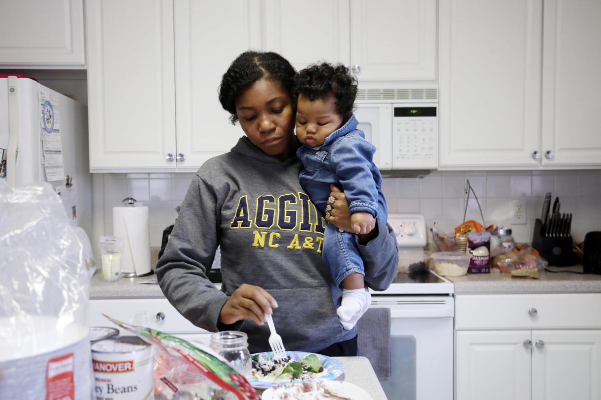 Jessica Murrell Berryman, 35, holds her third child, Richard, as she grabs lunch at the family’s Durham home, Dec. 6, 2019.