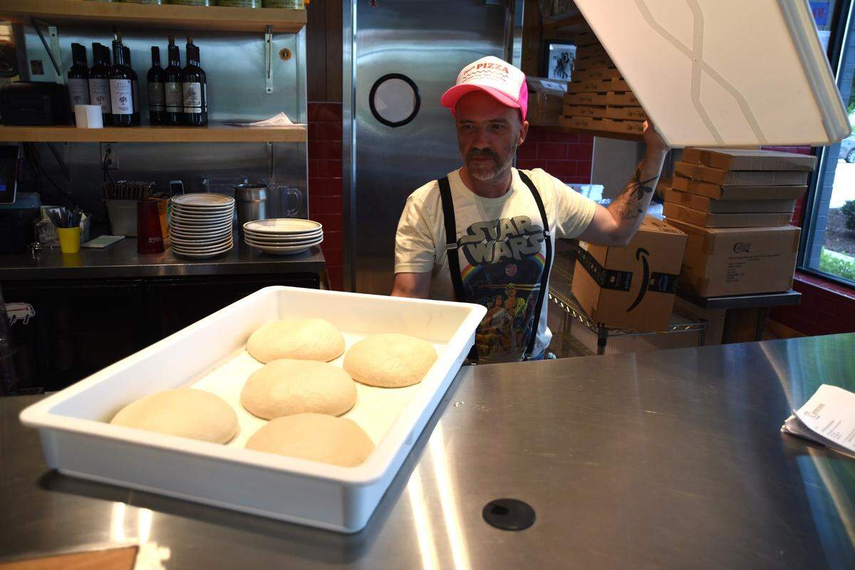 Chef Tom Cuomo shows off the dough at Dino’s, where every pizza is around 16 inches.