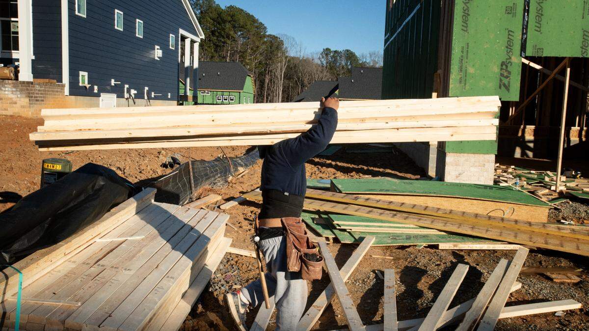 The N.C. Building Code Council is seeking changes that would require increased insulation and energy efficiency standards in new buildings. Here, a worker carries lumber for framing of the second story of one of many homes under construction in the Green Level area of western Wake County.