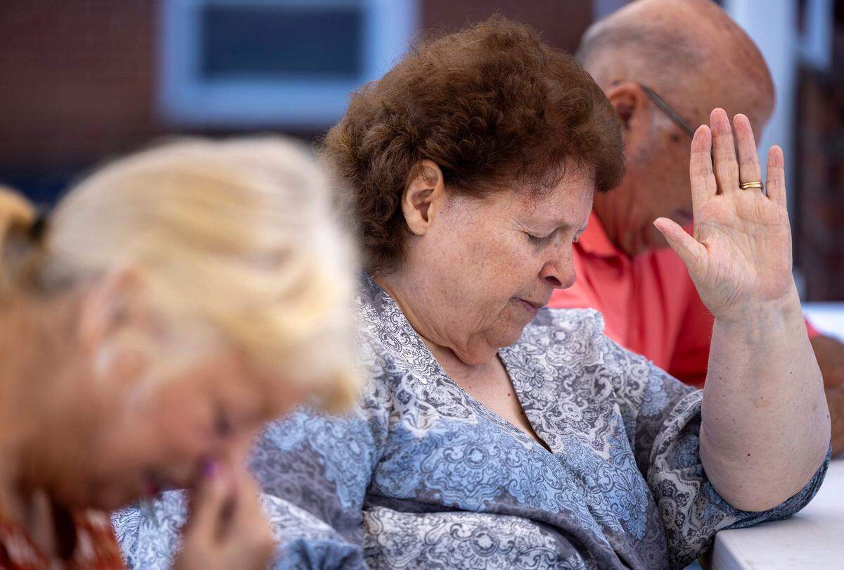 Kathy Ricker prays for those in need at Salem Free Will Baptist Church on Sunday, October 6, 2024 in Old Fort, N.C.  Still without power more than a week after Hurricane Helene passed through the region, they gathered outside in the church parking lot.