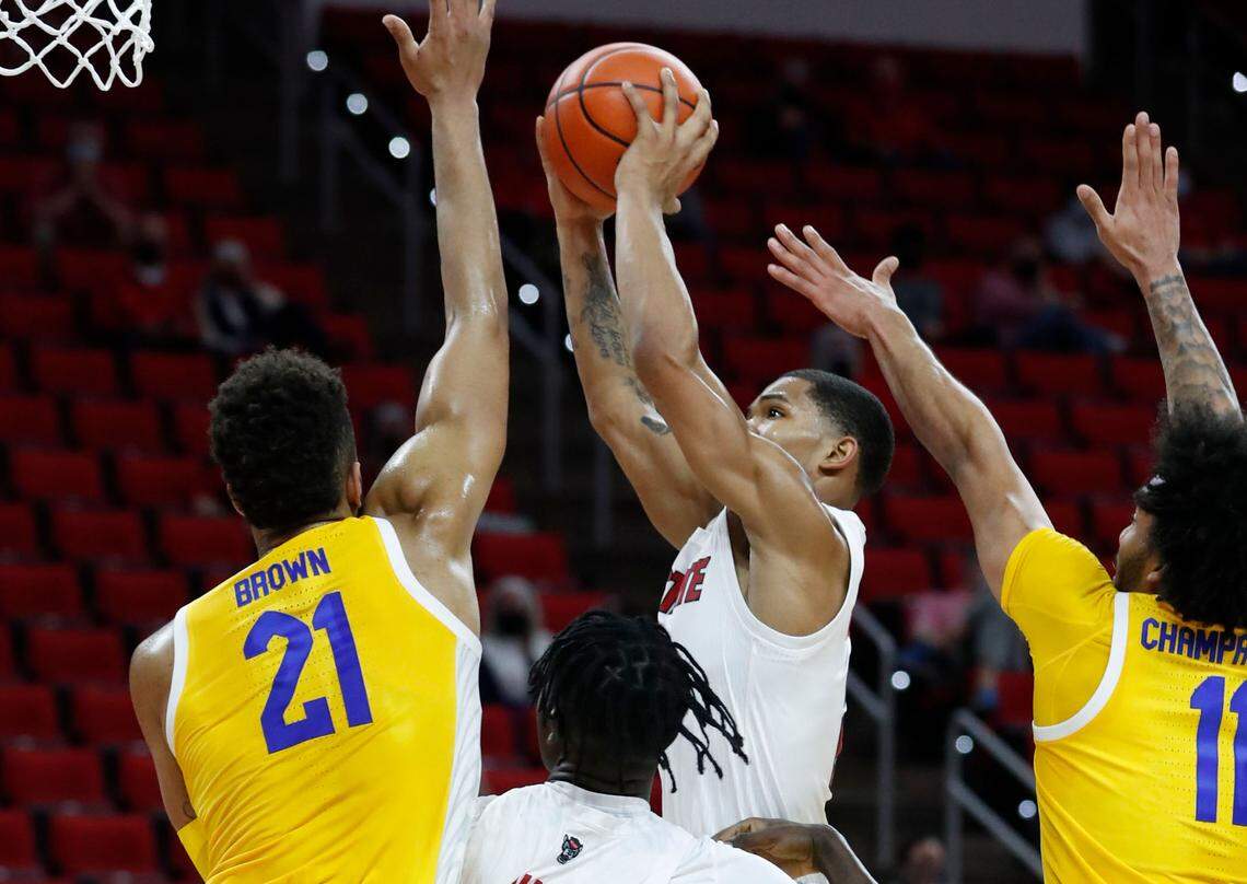 N.C. State’s Shakeel Moore (2) shoots during the first half of N.C. State’s game against Pittsburgh at PNC Arena in Raleigh, N.C., Sunday, February 28, 2021. Pittsburgh’s Terrell Brown (21) and Pittsburgh’s Justin Champagnie (11) defend.