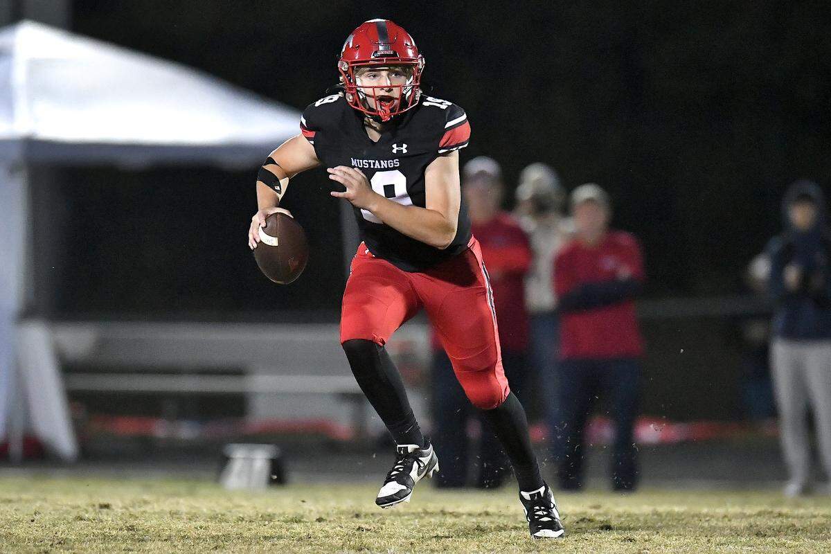 Middle Creek quarterback Hawke Shoenfeld (19) runs and looks to pass against Apex Friendship during the second half. The Middle Creek Mustangs and the Apex Friendship Patriots met in a football game in Cary, N.C. on October 25, 2024.