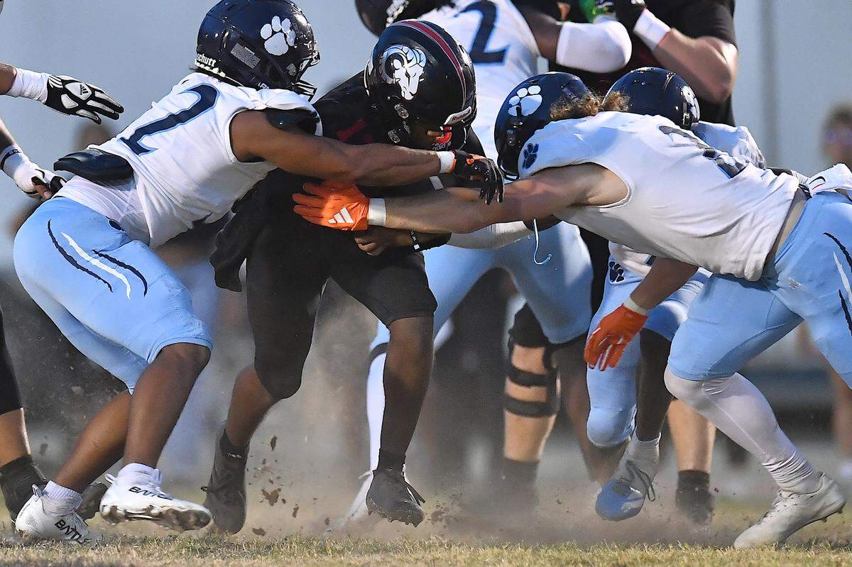 Rolesville quarterback Kaleb Williams (13) runs through the middle for yardage against Millbrook linebackers Quinton Cypher (2) and Carsen Adams (32) during the first half. The Millbrook Wildcats and the Rolesville Rams met in a conference football game in Rolesville, N.C. September 26, 2025