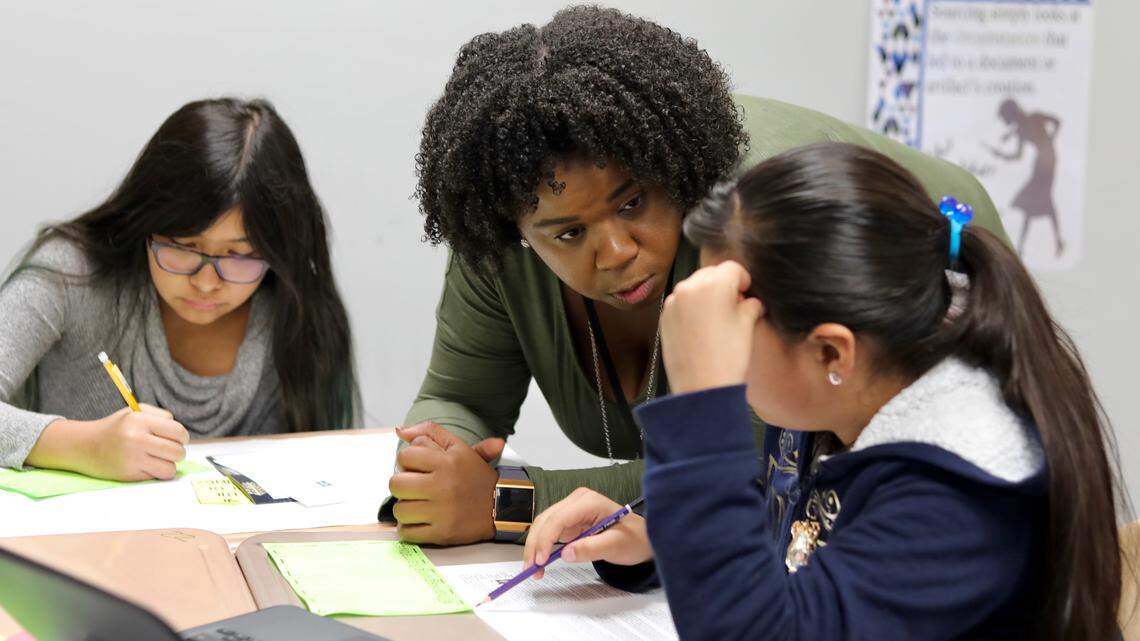 Social studies teacher Keisha Worthey answers a question asked by Ana Degado-Carmona (right) while Kayla Vargas-Gomez (left) works on a mind map during a lesson on being culturally responsible during Thanksgiving at East Millbrook Middle School in Raleigh.