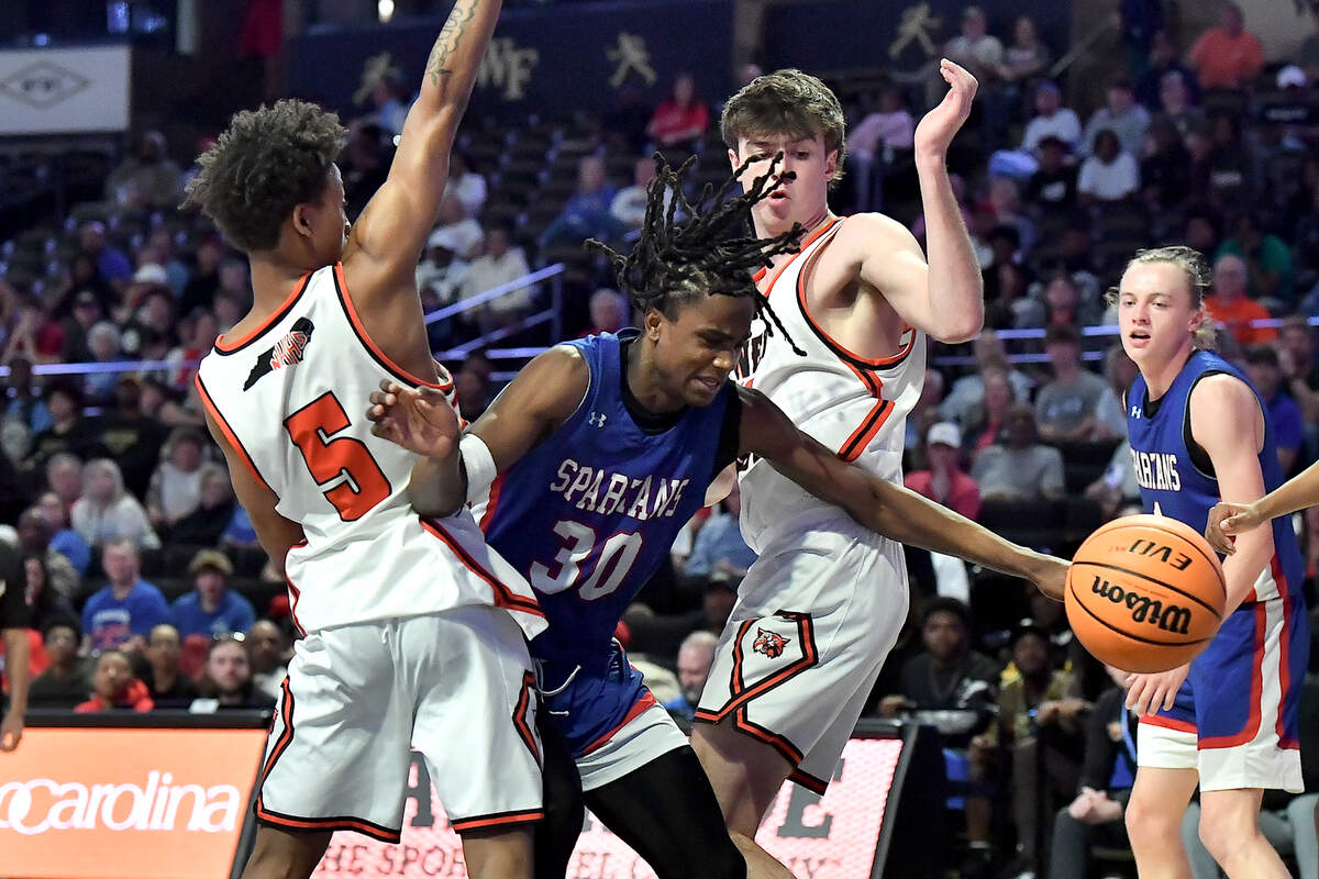 Sanderson’s Malakhi Murphy (30) tries to save the ball between New Hanover’s Nolan Billings (34) and Rodmik Allen (5) during the first half. The Sanderson Spartans and the New Hanover Wildcats met in the NCHSAA 4A East Regional Final in Winston-Salem, N.C. on March 12, 2025.