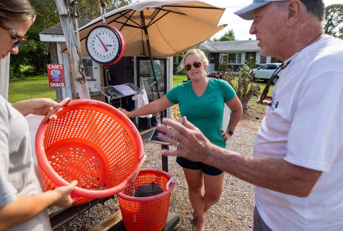 Savannah Sessoms, left, and Monica Smith sell fresh shrimp to Gerald Winstead at Miss Gina’s Fresh Shrimp. The Smiths call the converted child’s playhouse “the shack” and use it as an office space on the side of Highway 70 in Beaufort, where they sell shrimp.