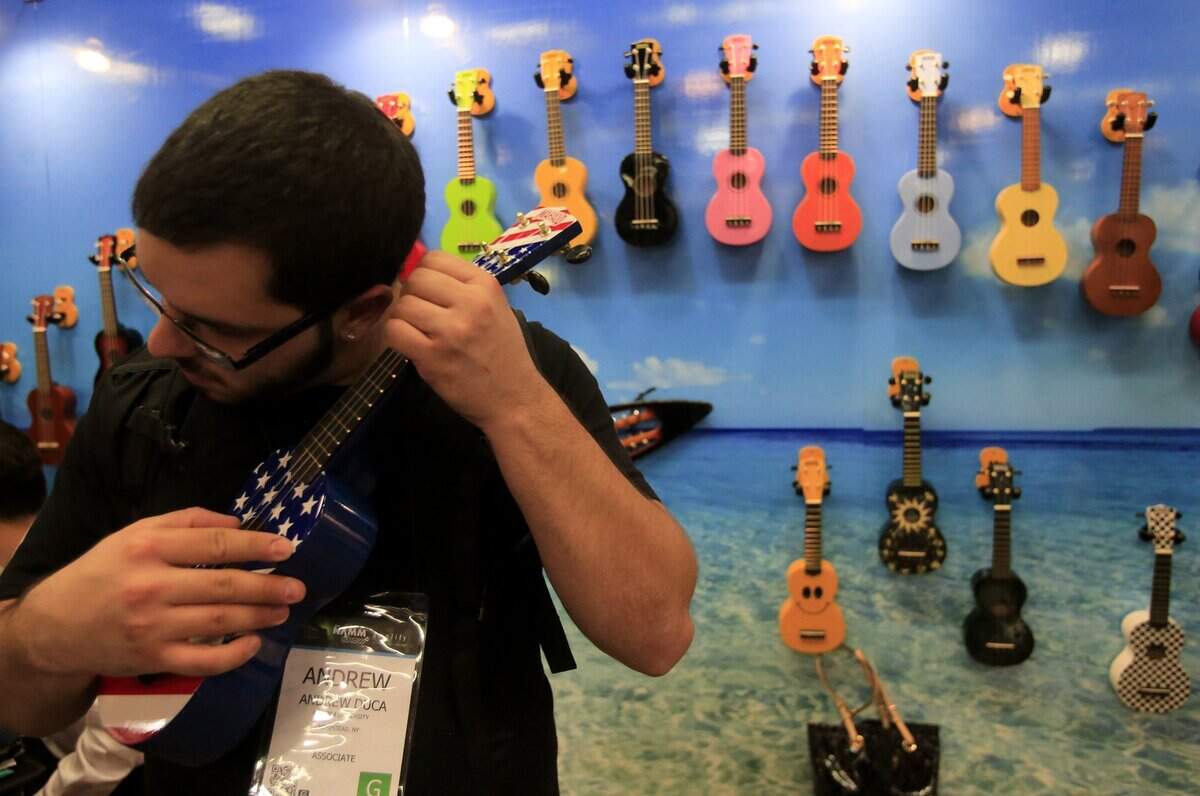 Andrew Duca listens to the sounds of a ukulele in the Mahalo Ukulele booth during the NAMM show at the Anaheim Convention Center in 2014. Why not have your kid join him?